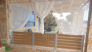 A stone-walled balcony with a wooden bench, a table, and a chair. - Maritinas Stone Apartment On The Beach (Pyrgos)