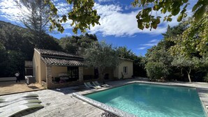 Une piscine à l’eau claire, entourée d’une terrasse carrelée et de chaises longues.