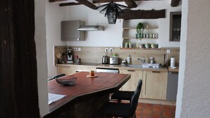 Une cuisine dotée d’un îlot central en bois, de tabourets de bar, d’un luminaire suspendu et d’un pare-feu en carreaux.