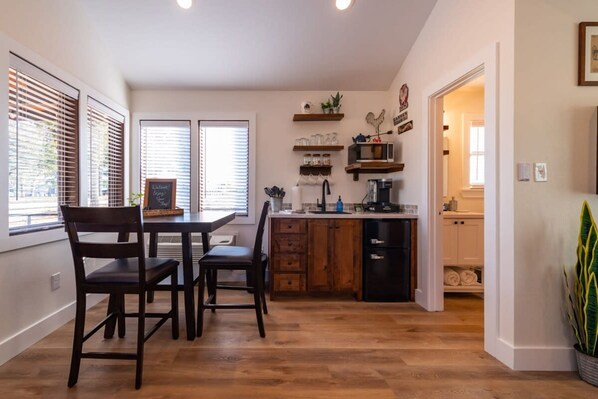 Una cocina moderna con armarios de madera, una mesa de comedor con sillas y un microondas empotrado.