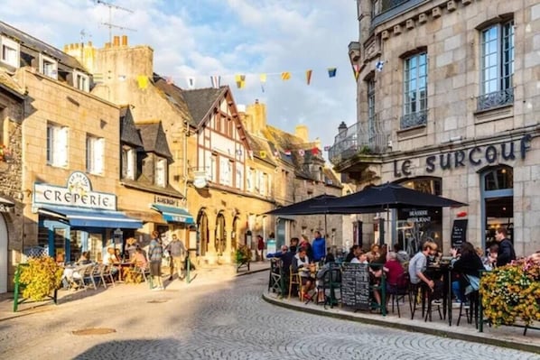 Eine Kopfsteinpflasterstraße mit Straßencafés und Restaurants, darunter 'Le Surcouf'.