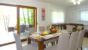 A dining area with a table set for six, a sofa, and a view of the outdoors. - House Kolpa Paradise Whirlpool And Sauna (Metlika)