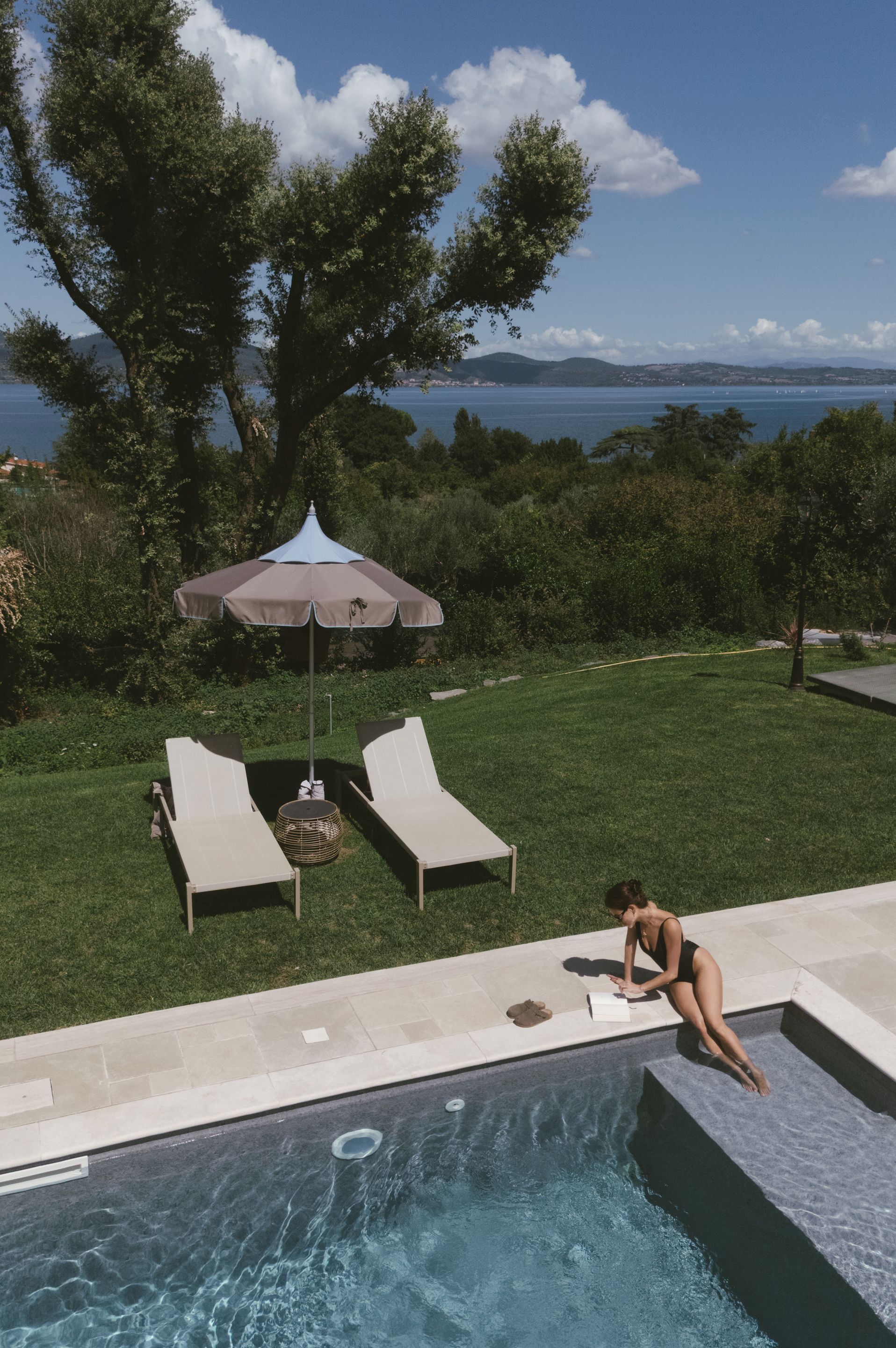 Ein Pool mit Meerblick, zwei Liegestühle und ein Sonnenschirm.