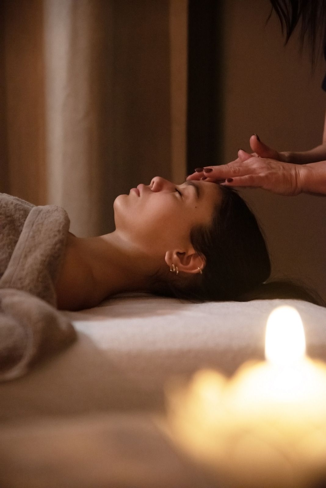 Eine Person erhält eine Massage, im Vordergrund brennt eine Kerze.