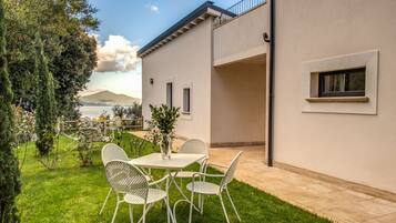 Une maison moderne dotée d’un patio, d’une table à manger avec des chaises, et offrant une vue sur une montagne et un lac.