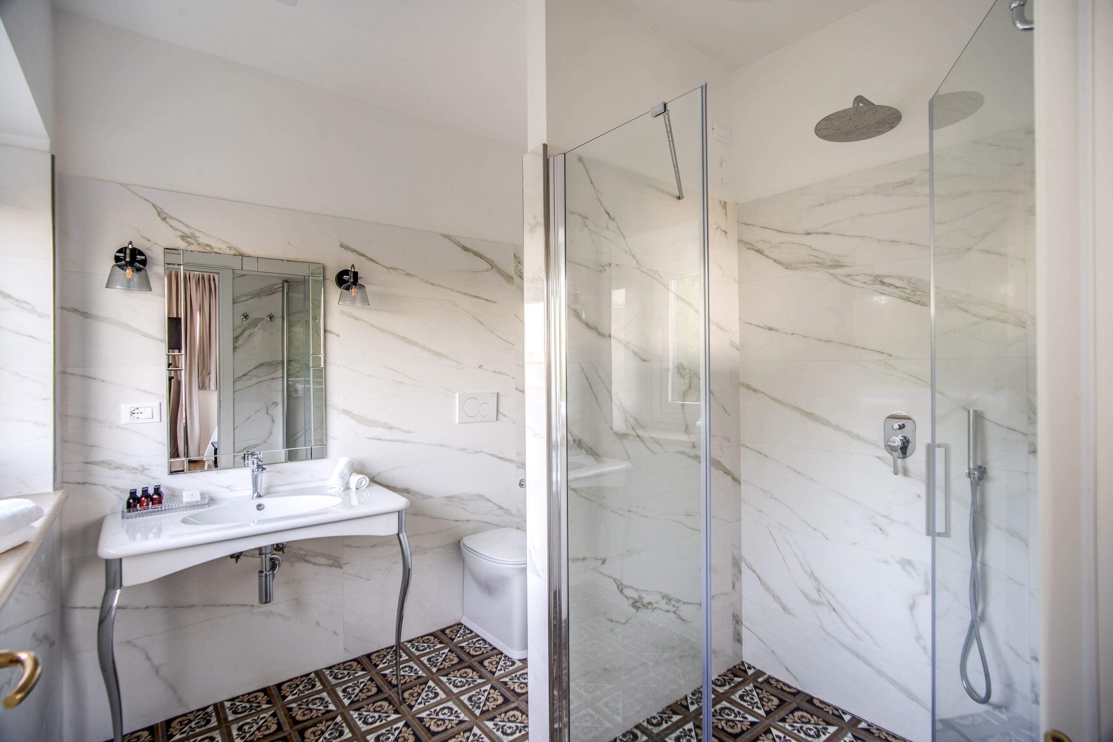 A modern bathroom with a glass-enclosed shower, a white sink, and a mirror.