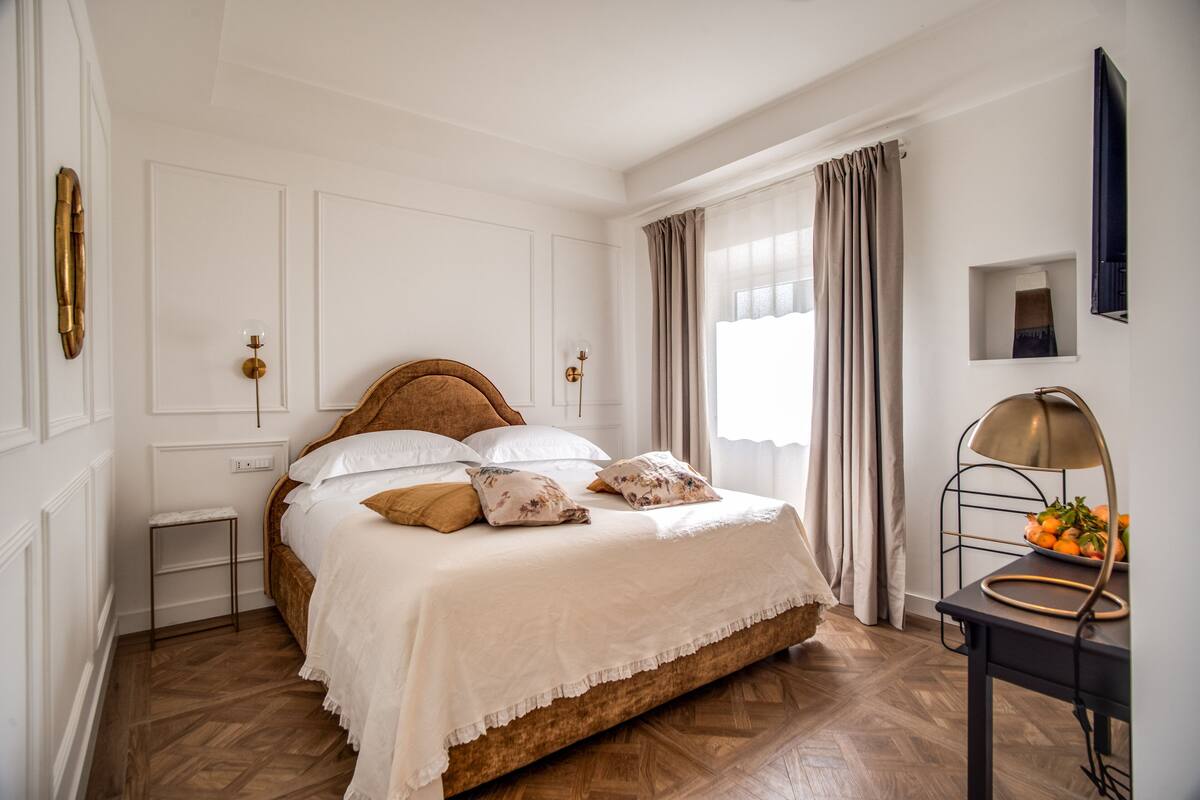 Ein ordentlich eingerichtetes Schlafzimmer mit einem Holzbett, weißer Bettwäsche, einem kleinen Nachttisch und einer Lampe.