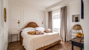 Une chambre à coucher bien rangée, avec un lit en bois, du linge de lit blanc, une petite table de chevet et une lampe.