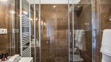 Un baño moderno con cabina de ducha de vidrio, un lavamanos blanco y suelo estampado.