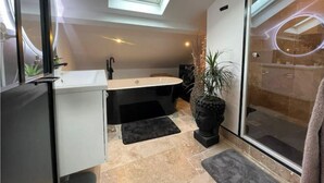 A modern bathroom with a skylight, a freestanding bathtub, and a large mirror. - Attic studio with top-of-the-range amenities (Villemomble)