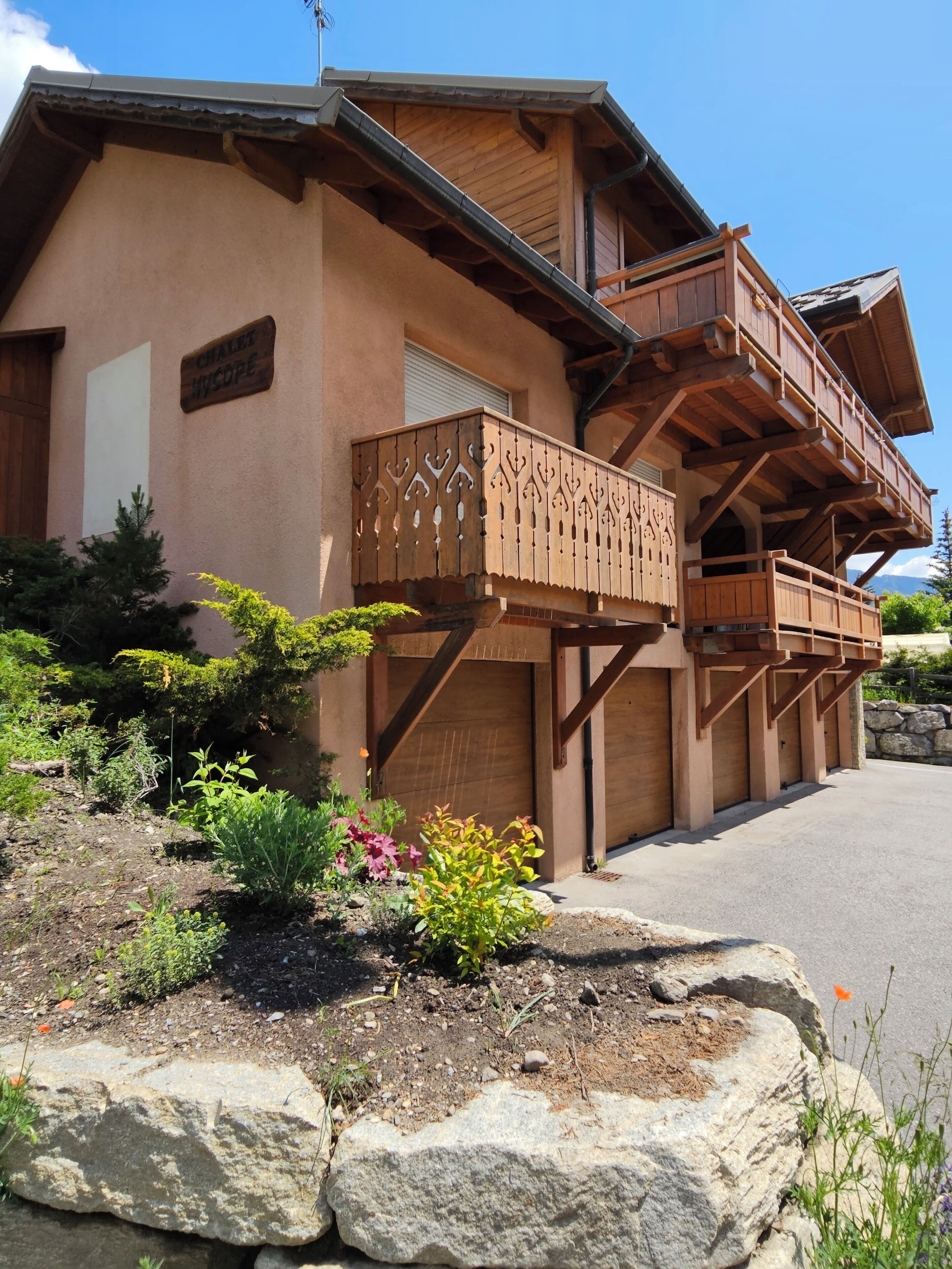A chalet with a wooden balcony, a stone facade, and a sign indicating it is a chalet.