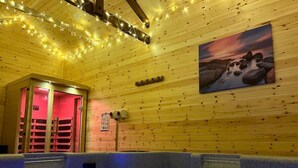A wooden interior with a hot tub, string lights, and a painting of rocks. - Orchard Barn Spa, exclusively for you, New Forest (Sandleheath)