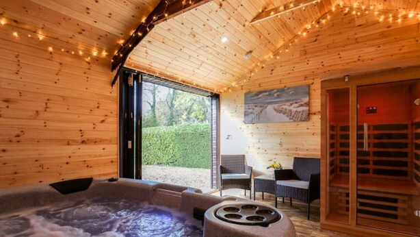 A wooden interior with a hot tub, seating area, and a sauna. - Orchard Barn Spa, exclusively for you, New Forest (Sandleheath)