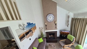 Una sala de estar moderna con chimenea, un sofá, una mesa de centro y un televisor.