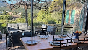 Un espace de restauration en plein air avec une table dressée pour deux personnes, entourée de fauteuils confortables et d’un canapé.