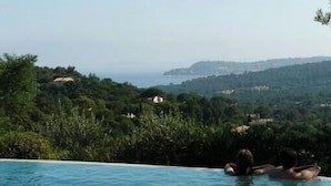 Une piscine offrant une vue sur un paysage luxuriant et des collines lointaines.