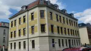 A multi-story building with a corner entrance, large windows, and a flat roof.