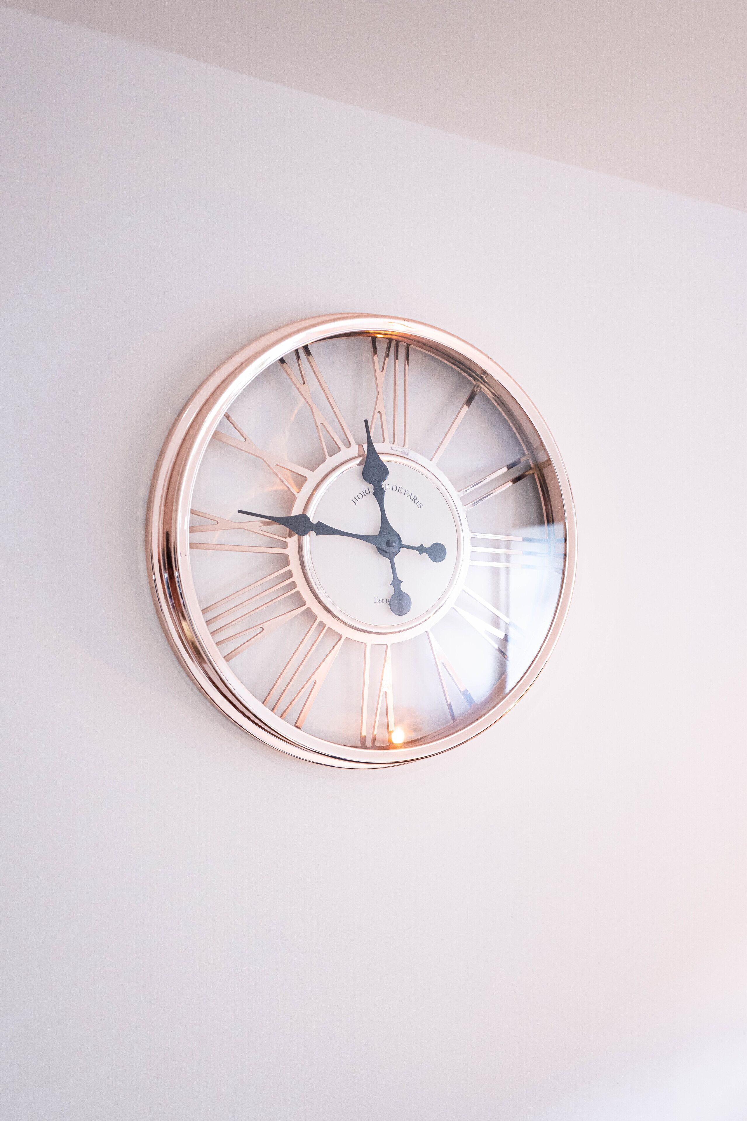 Une horloge murale ronde, dotée de chiffres romains et d’un design minimaliste.