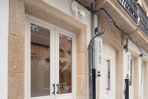 Fachada de edificio con detalles de piedra, puerta de vidrio y letrero que dice 'Noro Plaza Travel Home'.
