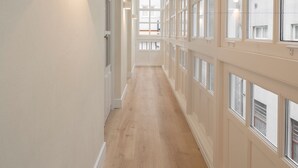 A long, narrow hallway with large windows on one side and a wall-mounted light fixture on the other. - NORO Plaza (A Coruña)