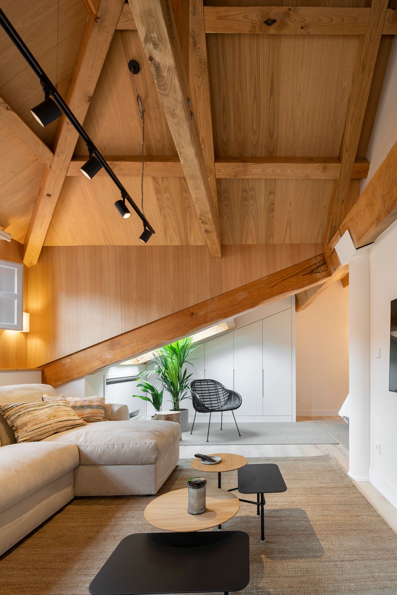 Un espace de vie moderne de style « loft », avec des poutres en bois apparentes, un canapé, une table basse et un fauteuil.