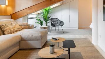 Un espace de vie moderne de style « loft », avec des poutres en bois apparentes, un canapé, une table basse et un fauteuil.