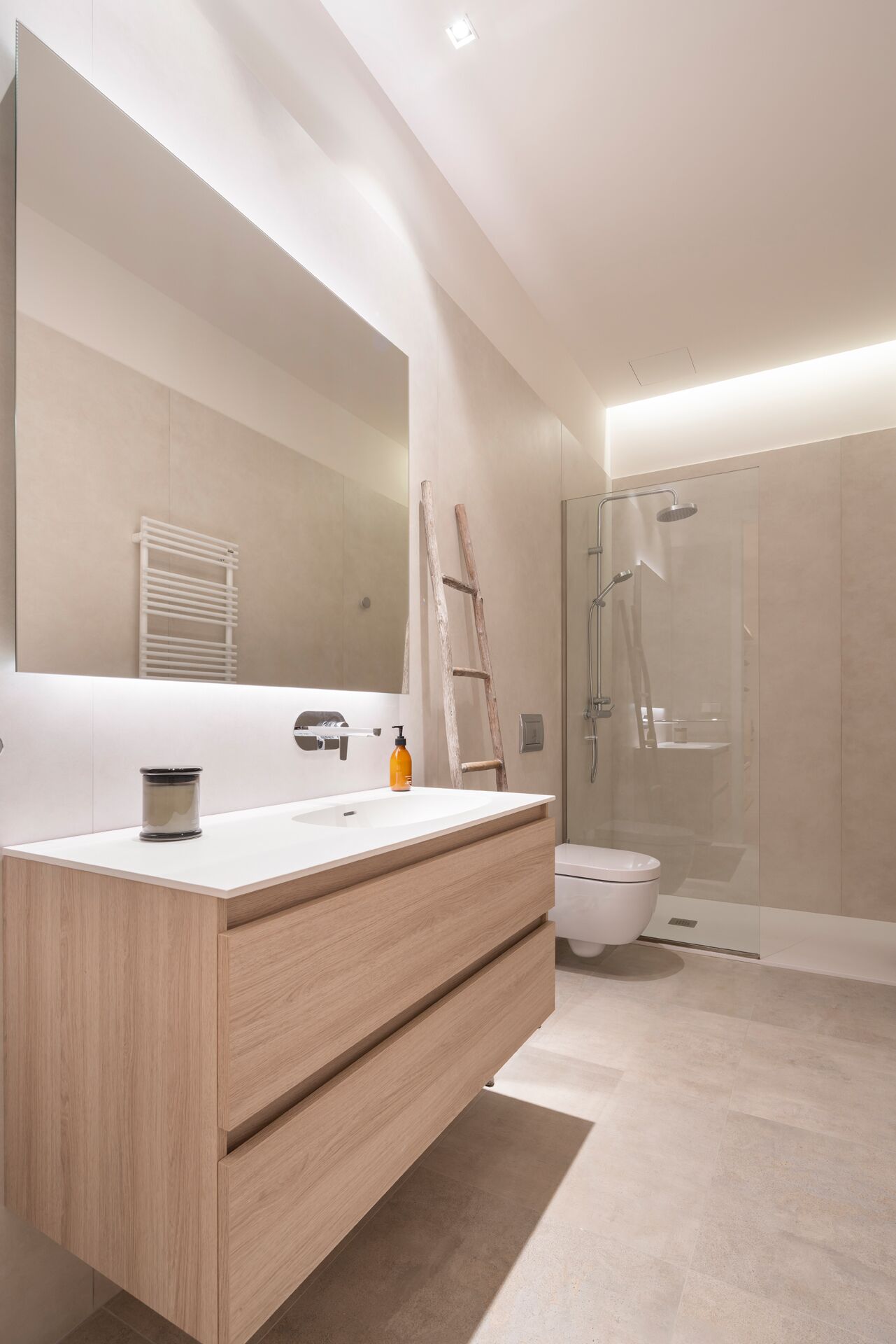 Un baño moderno con un espejo grande, un tocador de madera, ducha e inodoro.