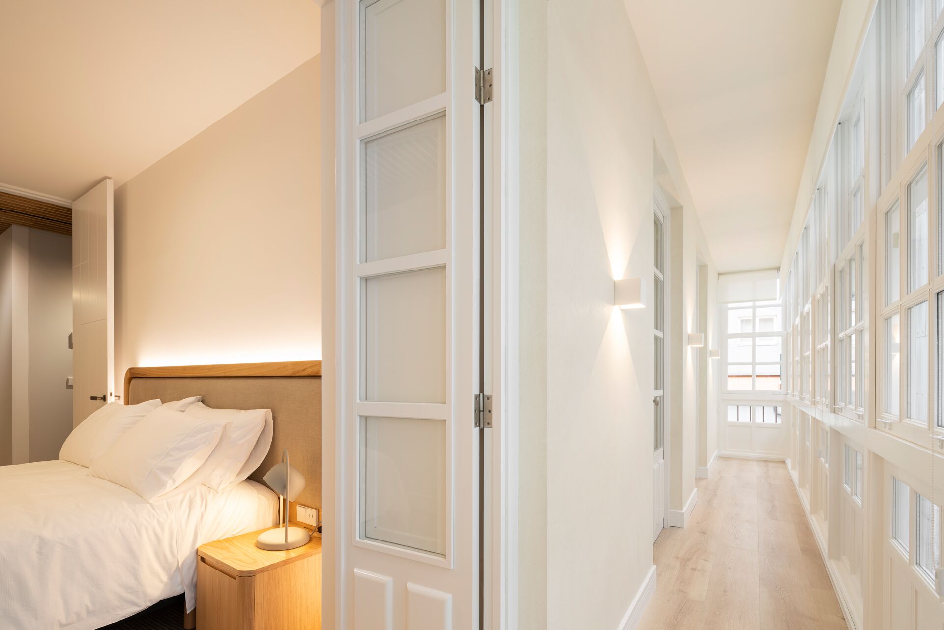 Hotellihuone, jossa on sänky, yöpöytä ja pienempi sivupöytä.