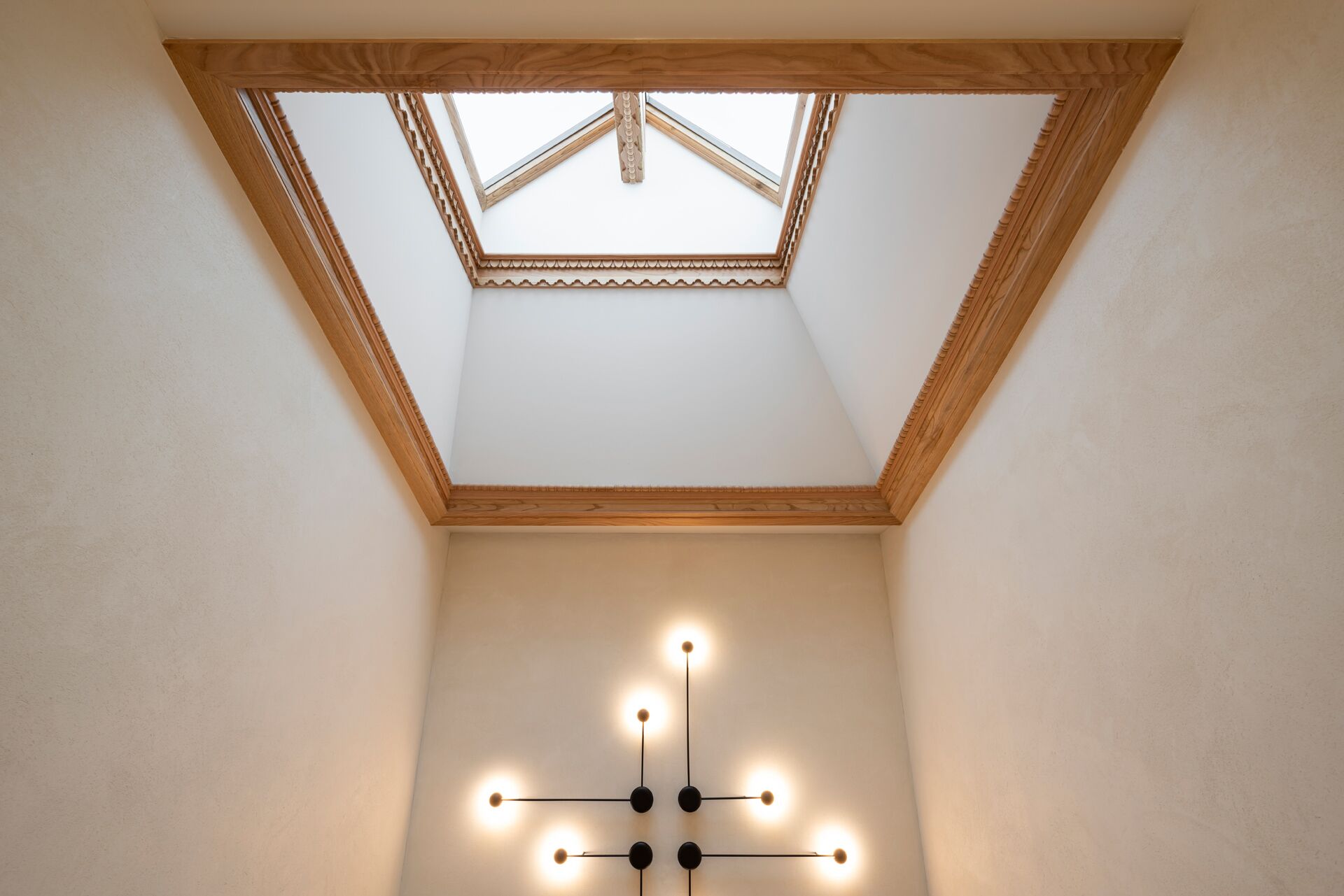 A skylight with a wooden frame and a cross-shaped light fixture below it.