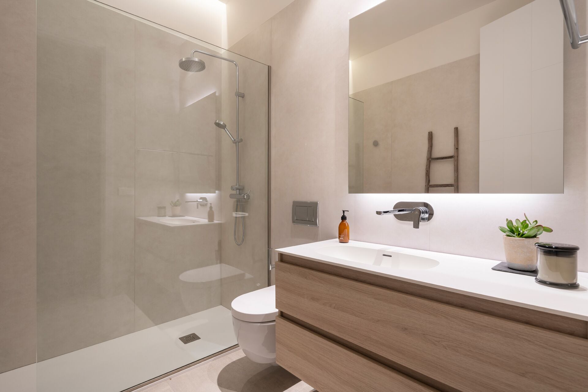 A modern bathroom with a glass shower enclosure, a white toilet, a wooden vanity with a mirror, and a small potted plant.