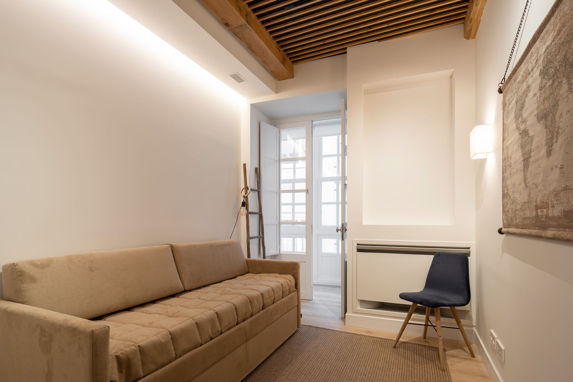 Habitación en tonos neutros con un sofá, un sillón y un radiador.