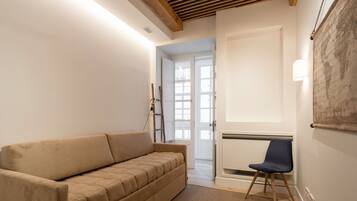 Habitación en tonos neutros con un sofá, un sillón y un radiador.