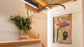 A modern interior with a wooden staircase, a blue rug, and a colorful abstract painting on the wall.