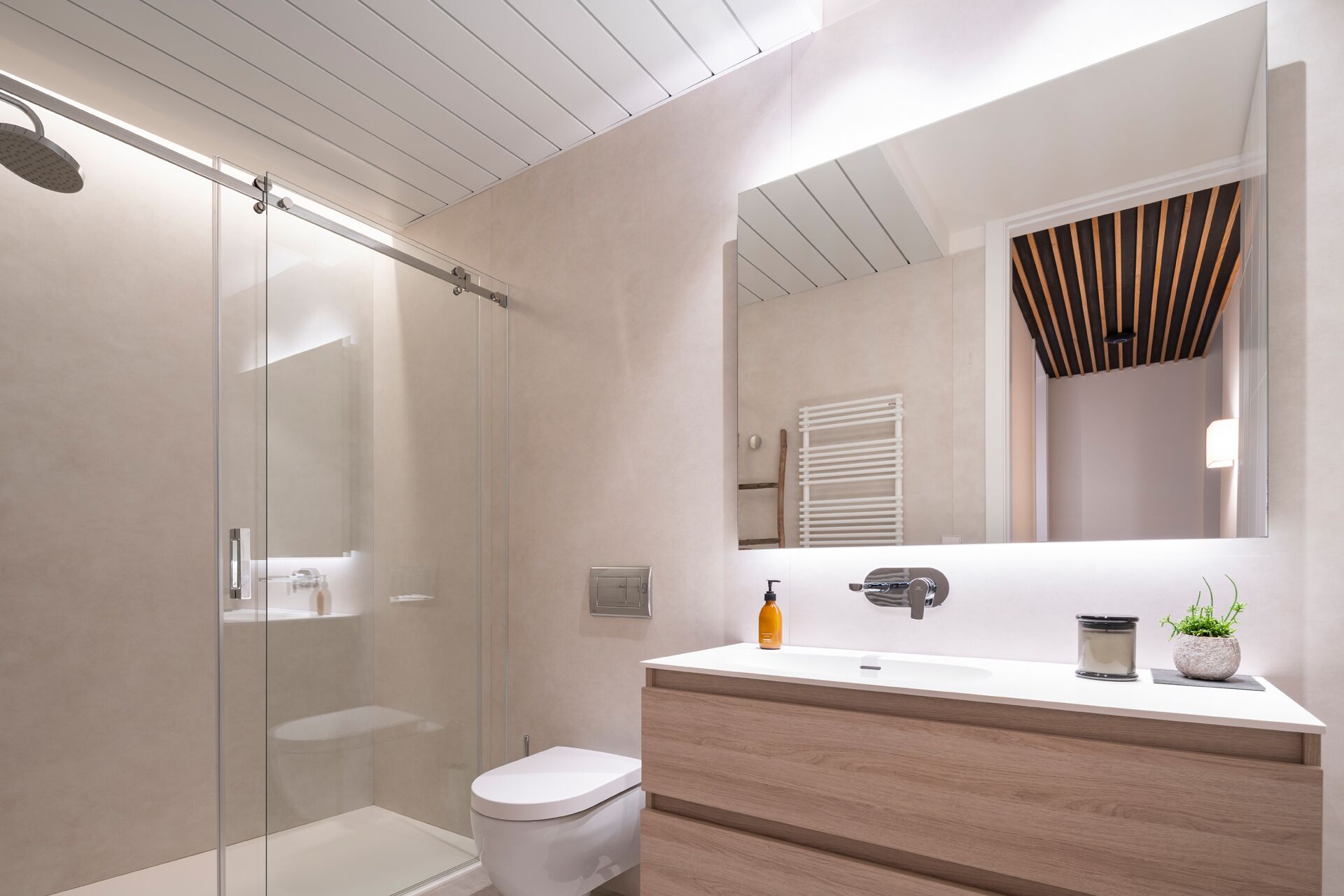 A modern bathroom with a glass shower enclosure, a white toilet, and a wooden vanity with a mirror.