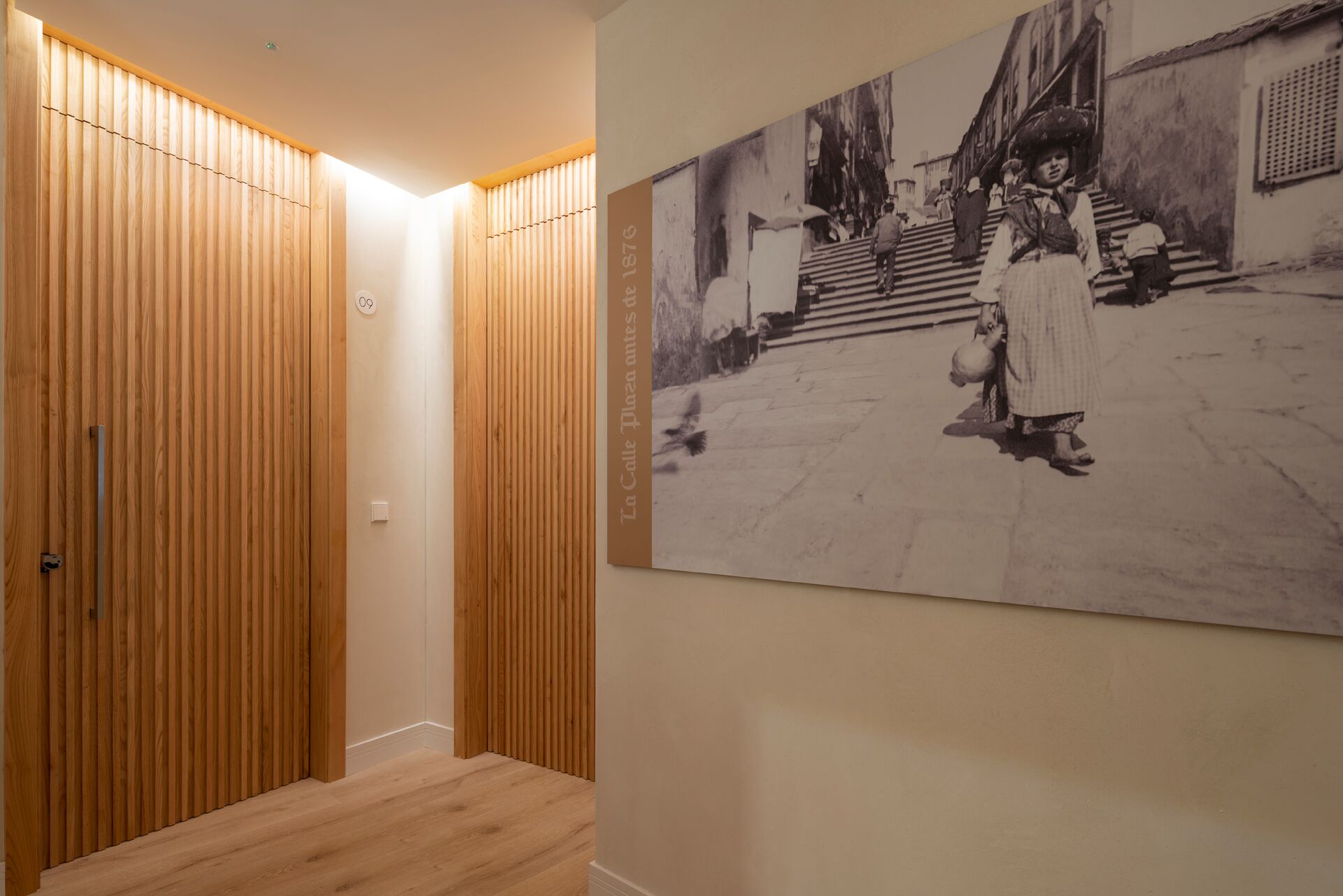 Een gang met houten lambrisering en een zwart-wit foto aan de muur.