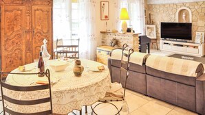 A cozy living room with a dining area, a stone fireplace, a television, and a sofa with a blanket. - Beautiful home in Espeluche (Espeluche)