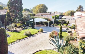 Stroll through a serene residential area with a beautifully manicured lawn, gravel driveway, and lush landscaped gardens.