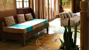 A wooden cabin interior with a bed, sofa, and potted plant. - Eliza Bungalow, luxury with sea view in Trancoso (Trancoso)