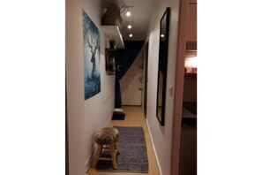 Staircase leads to an upper level, lined with framed artwork and a small stool.