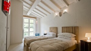 A bedroom with two beds, a window, and a door. - Design house in Tuscan style surrounded by nature (Pescaglia)