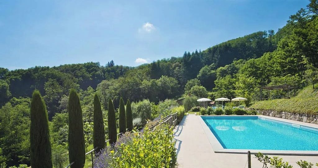 A swimming pool with a view of a lush green landscape and hills in the background.