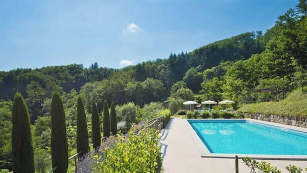 A swimming pool with a view of a lush green landscape and hills in the background.