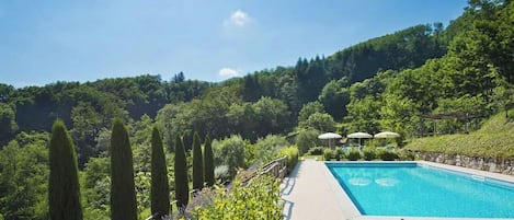 Una piscina con vistas a un paisaje verde exuberante y colinas al fondo.