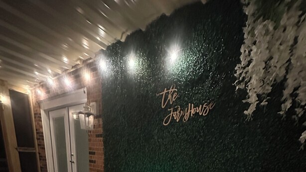 Ein Whirlpool mit grüner Wand und einem Neon-Schild, das „the Jolly House“ zeigt.