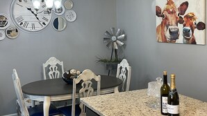 Ein Essbereich mit einem runden Tisch, Stühlen, einer Wanduhr, einer Windmühlen-Dekoration und einem Gemälde von Kühen.