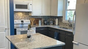 Eine Küche mit einer Granit Arbeitsplatte, weißen Schränken, einem Einbauofen und einem Kühlschrank.