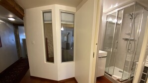 A modern bathroom with a glass shower enclosure, a white toilet, and a wooden floor. - Les Rêveries-beautiful apartment in the heart of the historic center (Annecy)