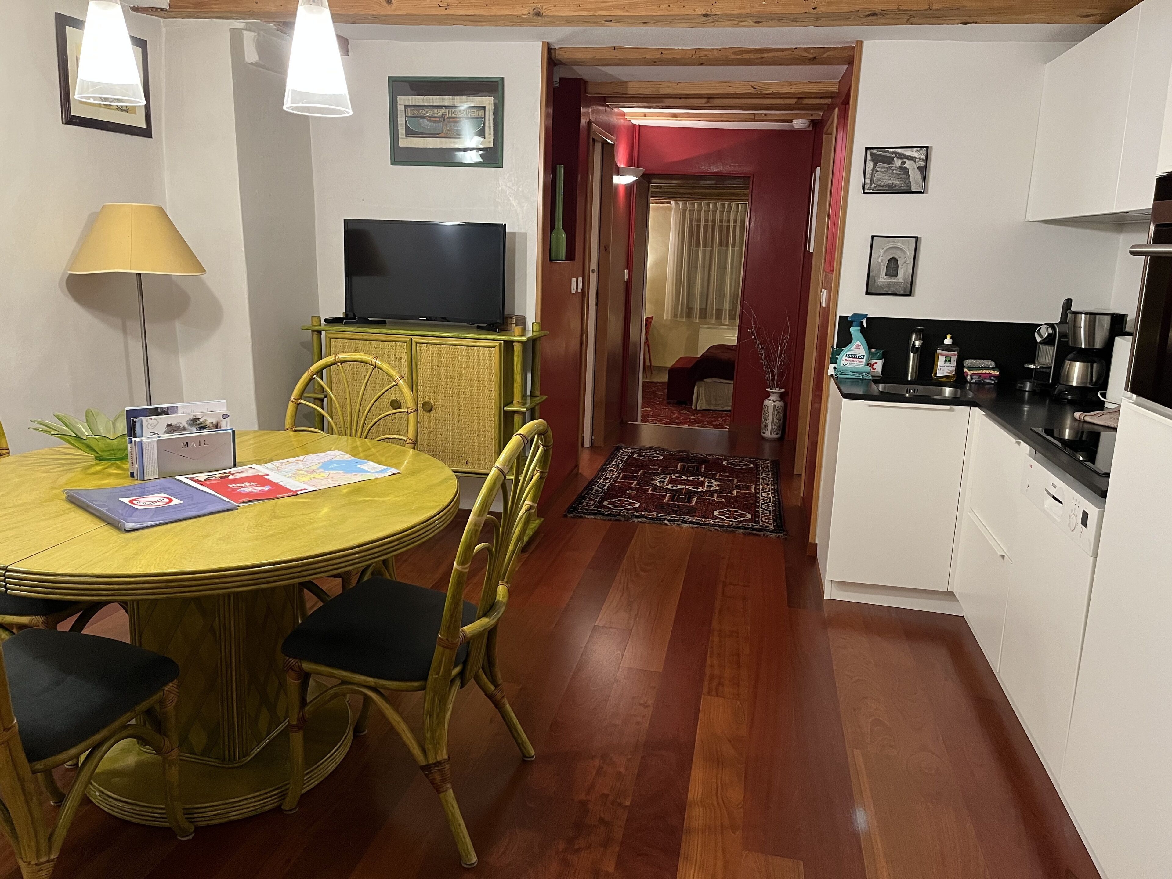 A dining area with a round table, chairs, a television, and a cabinet.
