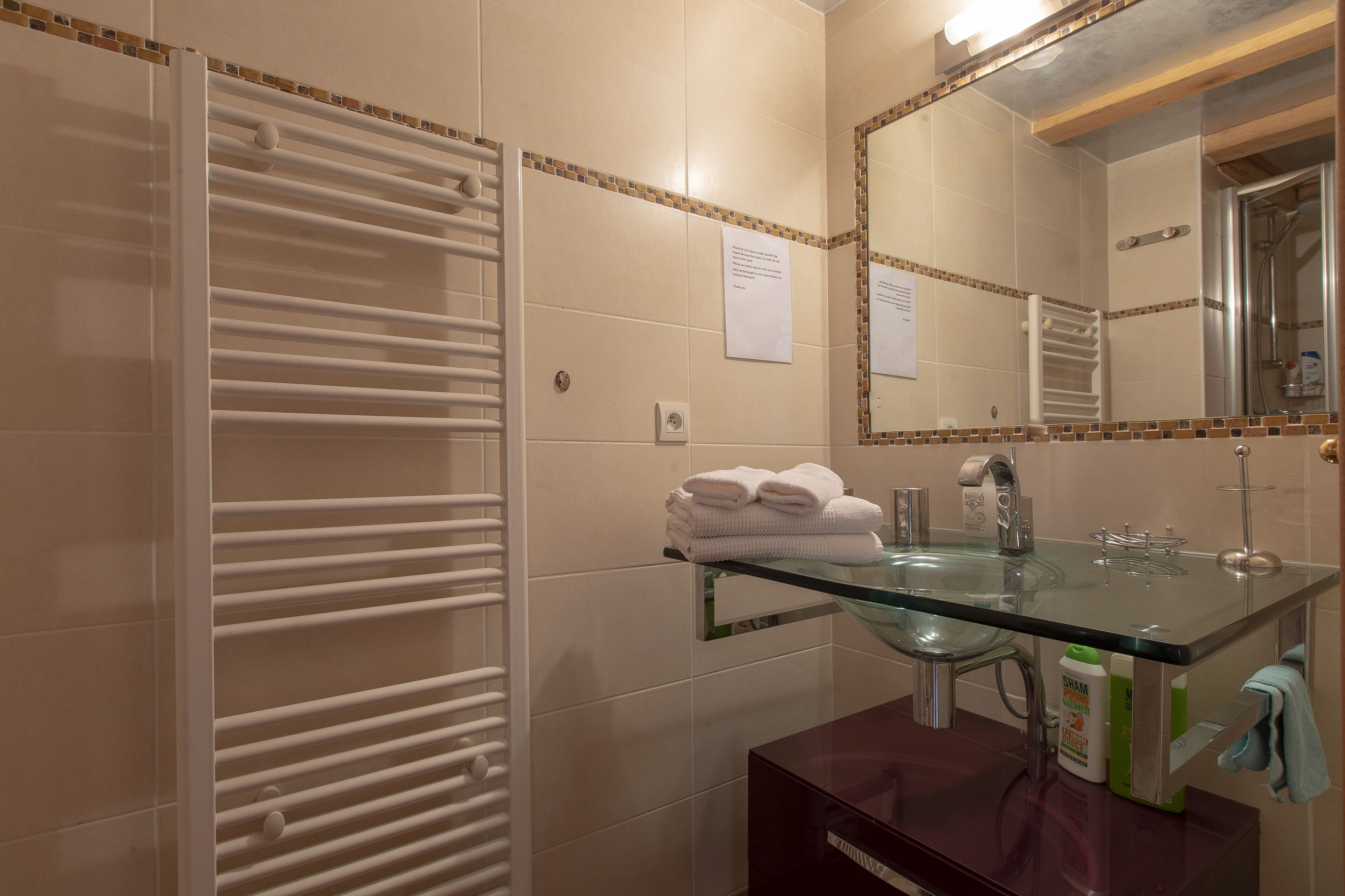 Un bagno con lavabo in vetro, portasciugamani bianco e uno specchio.
