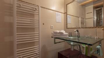 Un bagno con lavabo in vetro, portasciugamani bianco e uno specchio.